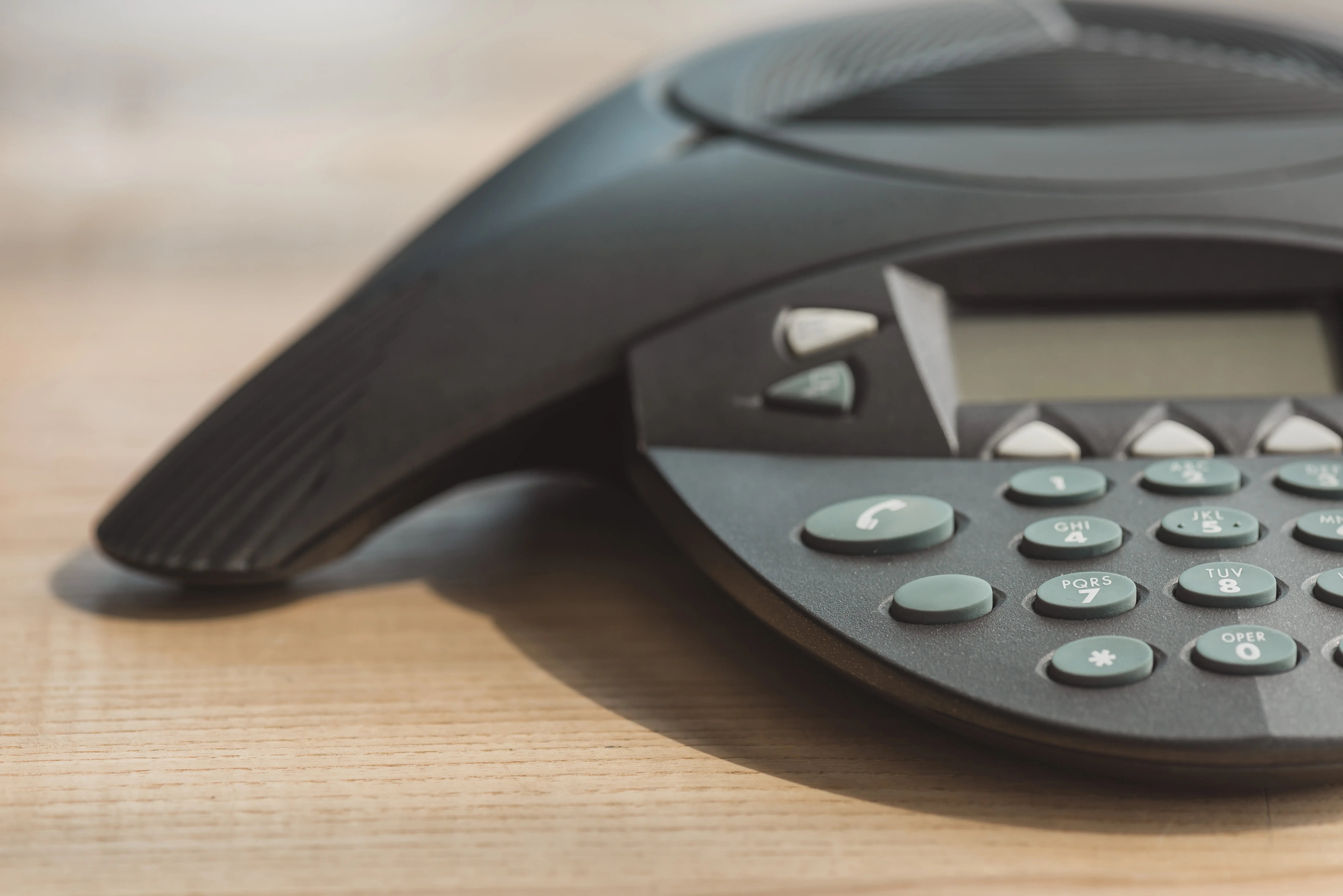 partial-view-of-conference-phone-on-wooden-table-a-2026-01-06-00-25-56-utc